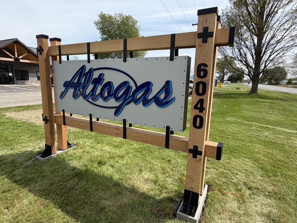 Altogas dimensional blue lettering on a white sign panel supported by timber posts with black hardware.